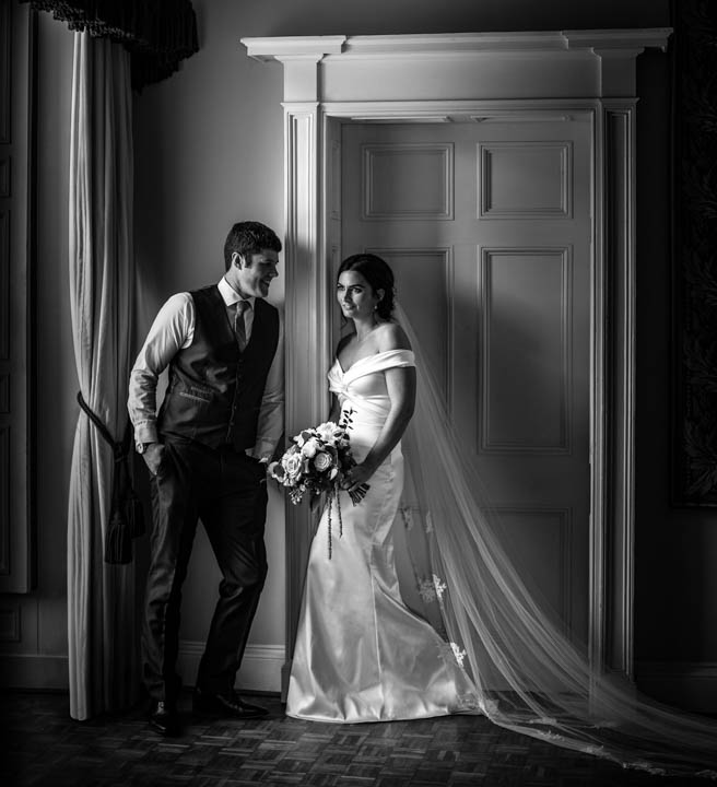 classical wedding photograph of bride and groom together at a large window